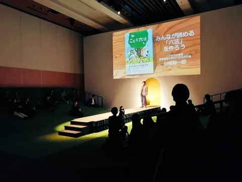 「みんなが読める『六法』を作ろう」と映したスクリーンの前で話す講演